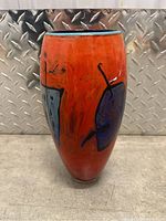 Front view of large orange glass vase with blue abstract shapes