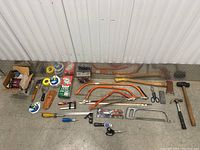 Photo of all tools laid out on floor showing the variety in the lot including saws, hammer, screwdrivers, putty knife, and box cutters.