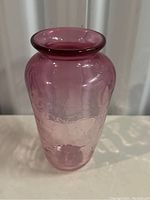 Tall pink glass vase with etched leaf/floral pattern, clear and transparent, light surface wear visible, rolled lip