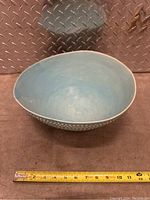 Front angle view of blue porcelain bowl showing interior and shape with measuring tape for scale.