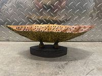 Front profile of the small bone boat sculpture showing the shape, coloration, and wooden stand.