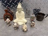 Front view showing all items in the lot including the Buddha statue, several figurines, vases, and the silver mug.