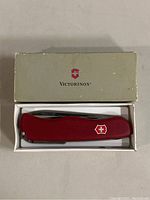 Red Victorinox Swiss Army Knife in original cream-colored box with Victorinox logo on top.