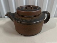 Side view of the brown ceramic tea pot showing spout, handle and lid