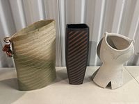 Three ceramic vases: light green textured vase, striped tall rectangular vase, and white sculptural vase.