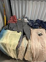 Photo showing multiple clothing items including skirts, jackets, and scarves laid out on a blanket.