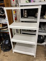 Side front photo showing the full 4 tier white plastic shelving unit in an indoor setting with other household items in the background.