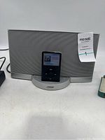 Bose SoundDock with Apple iPod Classic docked, showing front view of speaker and iPod screen.