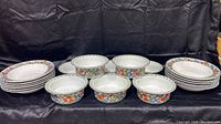 Full set of 12 shallow bowls stacked with 8 cereal soup bowls elevated and arranged behind them, showcasing floral Nordic Garden pattern.