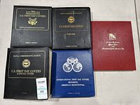 Five binders of U.S. First Day Cover stamps arranged on table showing front covers.