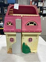Closed state of doll house showing windows, chimney moldings, pink roof, and fold line at center.