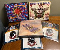 Four Grateful Dead CD sets along with 3 sheets of temporary tattoos showing skull and roses designs.