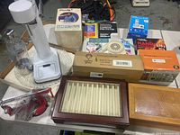 Photo showing all items spread on table including boxes for solar lights, hair dryer, answering system, pre-filters, hand warmers, apple peeler, glass jar, and upright white device.
