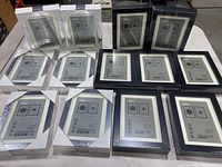 Top view of all 13 new packaged IKEA picture frames arranged in rows. Silver and black RISÅ frames in 5x7 and smaller sizes visible.