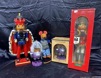 Group photo showing three nutcrackers and one plush mouse on black cloth background
