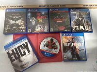 Top-down image of all six PS4 game cases and one Blu-ray DVD displayed together on a flat surface.