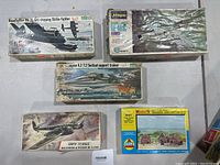 Top view of five airplane model kit boxes and one house kit box on flat surface.