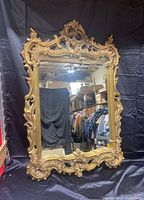 Full view of antique mirror with ornate gold gilt frame and rectangular glass.