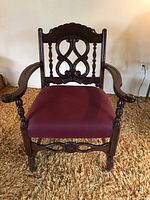 Front view of antique occasional chair showing carved wood backrest, armrests, and burgundy upholstered seat.