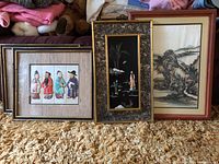 Photo showing four framed Asian-themed artwork pieces arranged on carpet, showcasing different styles and frame types.