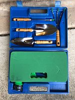 Blue plastic case open, showing wooden-handled gardening tools and green foam kneeling pad inside.