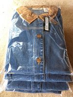 Stack of denim jackets in packaging showing brown buttons and tan collars