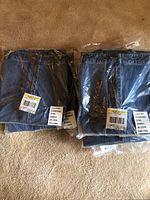 Seven pairs of stonewashed denim pants folded and sealed in original packaging, all size 16 regular.