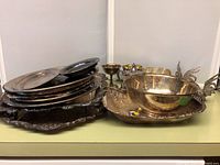 Photo of stacked silverplate platters and bowls with various etched and ornate designs.