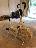 Side angle photo of a white Roadmaster AirWaves stationary bike with padded black seat and angled handlebars indoors.