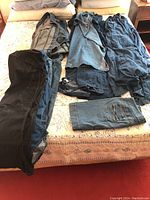 Denim jackets, pants, dresses, skirts arranged on bed showing fabric and styles.