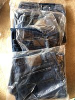 Four pairs of blue denim women's pants sealed individually in clear plastic packaging.