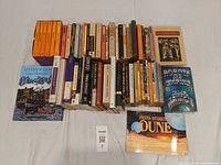 Top-down view of the books arranged in rows, showing spines and covers of classic fiction and sci-fi titles including Dune, Robots and Empire, Les Miserables, and Stephen Leacock's "Sunshine Sketches of a Little Town".