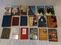 Books arranged in three rows on white cloth background, showing spines and front covers, includes various titles such as Bullet Park, Carol Shields, Margaret Atwood, Lawrence Durrell, and others