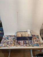Wide view of shoebox filled with baseball cards and loose cards spread on table.