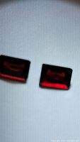 Photo of two rectangular orange-red almandine garnet gemstones placed on a white background showing their shape and color.