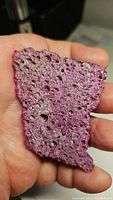 Flat rough ruby with honeycomb texture held in hand, showing size and natural surface details.