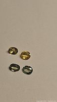 Four mixed oval cut sapphires of different colors shown on neutral background