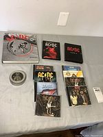 Photo showing all items in the lot: hardcover book, DVDs, CDs, and pocket watch laid out on a table.