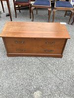 Front view of the cedar chest showing medium brown wood with two metal handles and a flat top