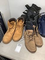 Full view of three pairs of men's boots on floor: Timberland work boots, Timberland casual boots, Columbia winter boots.