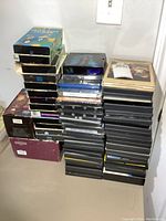 Stacks of DVDs and VHS tapes arranged on a surface, showing variety of cases including boxed sets.