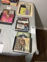 Top view of Rod Stewart DVD, Bob Dylan CDs, Jethro Tull CD, and Iggy Pop CD with book beneath