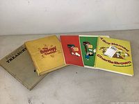 Overview photo of 5 Peanuts books laid out, showing title and cover art