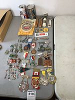 Top view showing full collection of pins, badges, openers, souvenir cans, coaster, and ribbons arranged on a table.