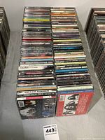 Stack of approximately 85 CDs arranged flat and stacked in columns showing mostly spine labels and some album visible covers.