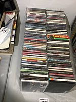 Photo showing a stack of approximately 85 rock and roll CDs laid out horizontally with visible spines including artists Bon Jovi, Sammy Hagar, ABBA, Matthew Good Band, and others.