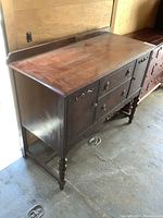 Full side view of vintage solid wood sideboard showing turned legs, carved apron and flat top with wear.