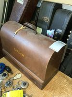 Front angled view of vintage Singer portable sewing machine in wooden case showing carry handle and gold lettering