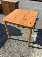 Small square solid wood dining table showing wood grain and removable legs