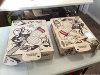 Two closed larger cardboard boxes featuring vintage baseball player illustration on lids and sides, holding major portion of the sports card collection.